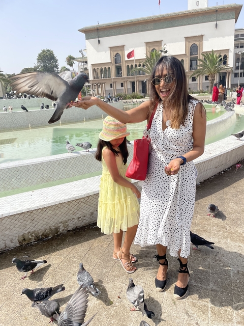 Person holding a pigeon with a child nearby.