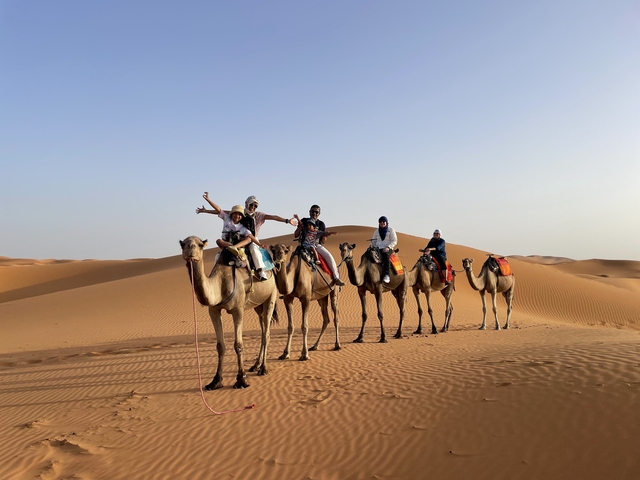 Group riding camels in the desert.