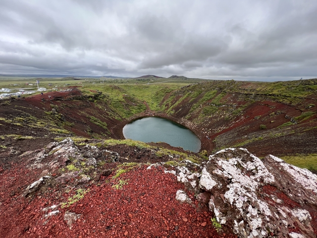 Colorful volcanic crater lake surrounded by vegetation.