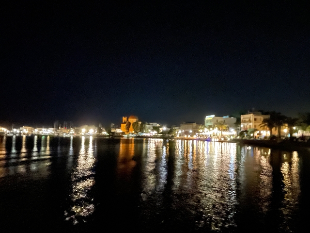       Nighttime view of a city waterfront with reflections in water.
  