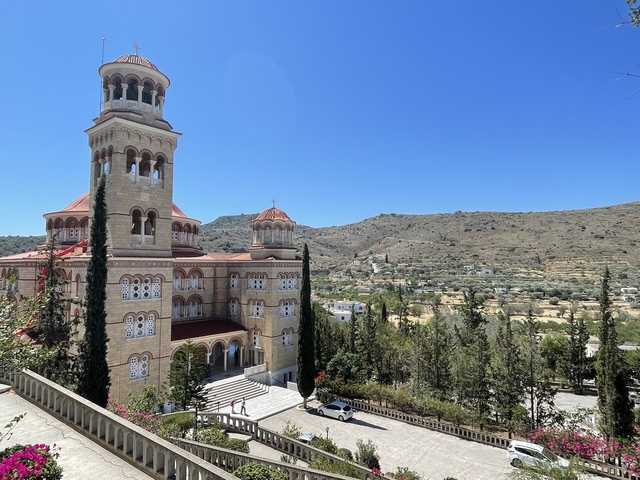       Large church with multiple domes surrounded by a hilly landscape.
  