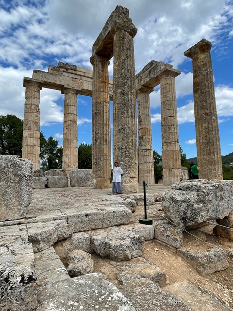       Tourists exploring an ancient Greek temple with tall columns.
  