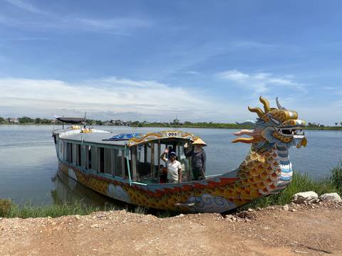 Two people on a colorful dragon boat in a river.