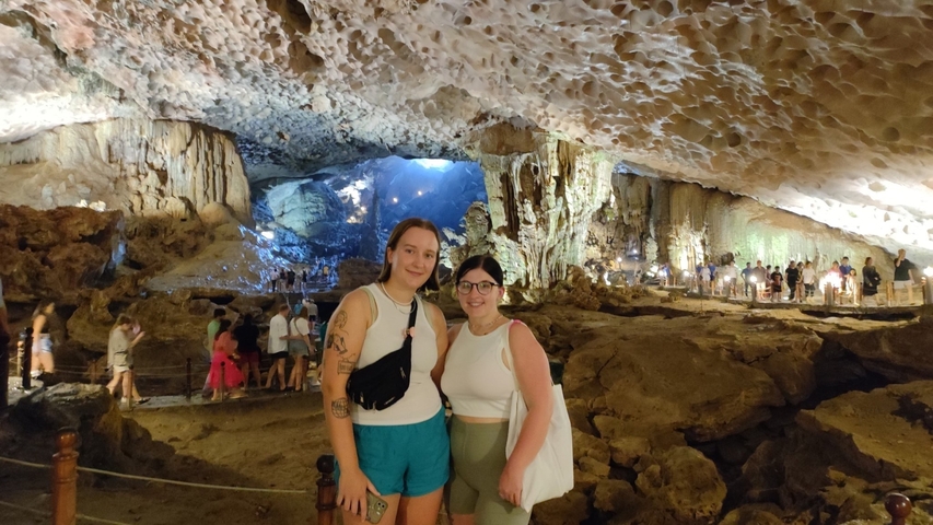       Two people standing in a cave with a scenic backdrop.
  