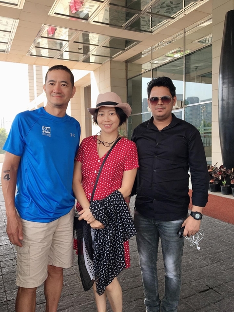       Three people posing together in front of architecture.
  