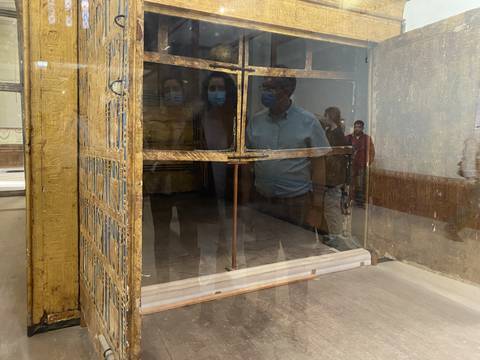 People looking at an ancient artifact inside a glass case.