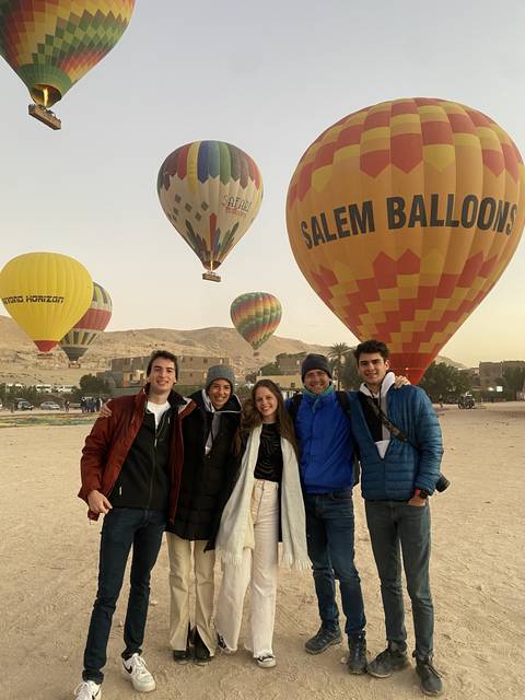 A group of people standing in front of hot air balloons.