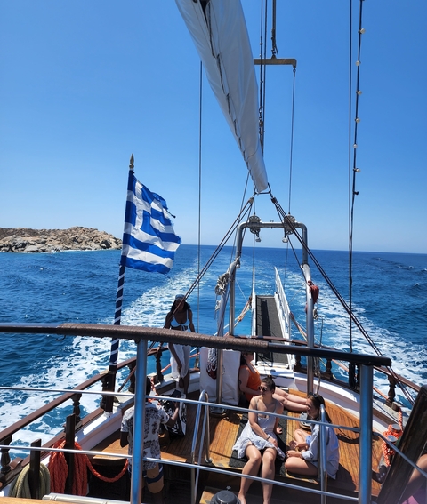       Woman on a boat with a Greek flag against the sea.
  