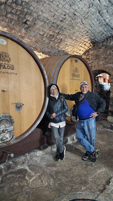 Two men standing with large wooden wine barrels.