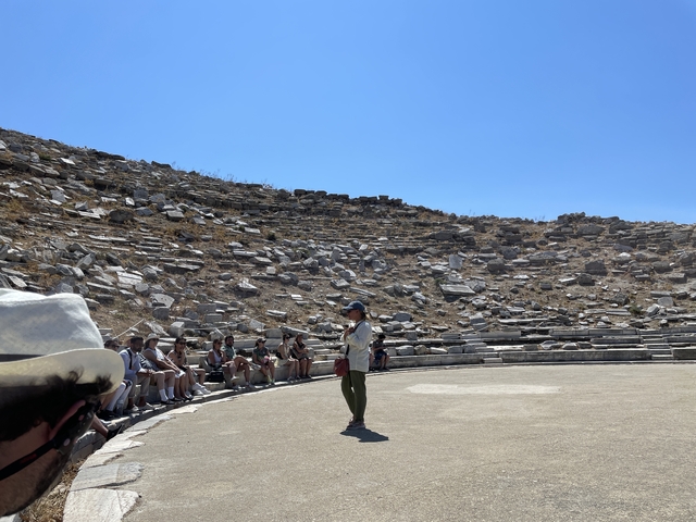       Tourist giving a tour at an ancient amphitheater in Greece.
  