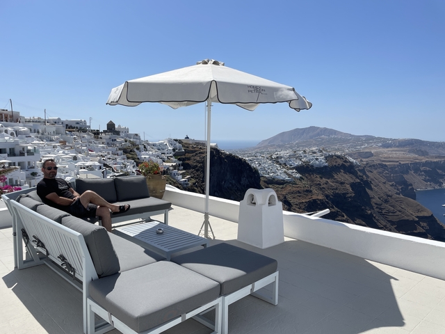       Person relaxing on a patio with a view of the caldera in Santorini.
  