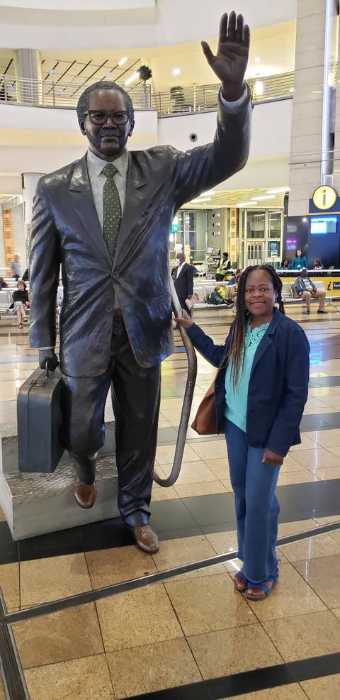 Person standing next to a large statue of a businessman.