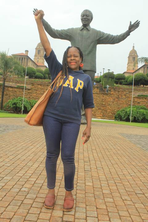 Person holding hand with a statue in a public space.