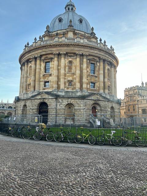       Radcliffe Camera building in Oxford with bicycles lined up.
  