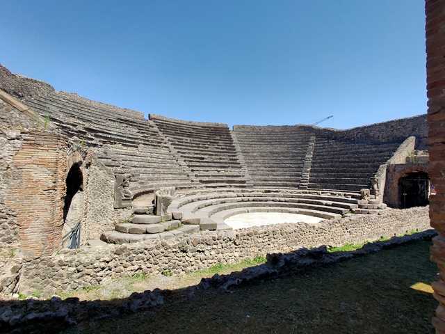       Ancient Roman amphitheater ruins under a clear sky.
  