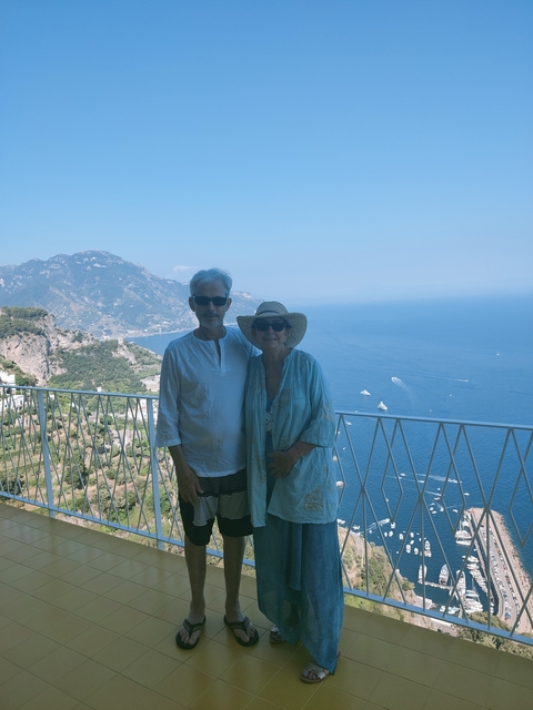       Couple standing on a balcony overlooking the sea and mountains
  