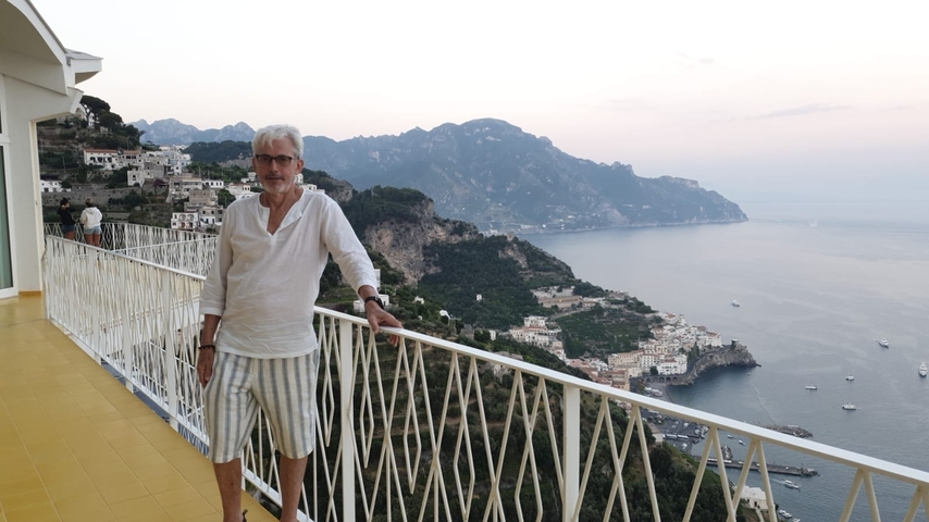       Man posing on a balcony with a panoramic view of the coastline
  