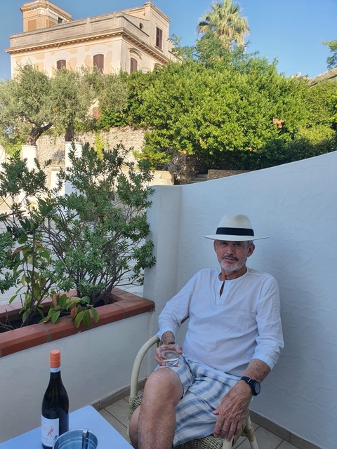       Man sitting on a terrace with greenery
  