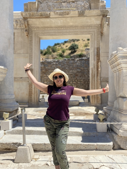       Woman with arms outstretched in front of ancient ruins
  