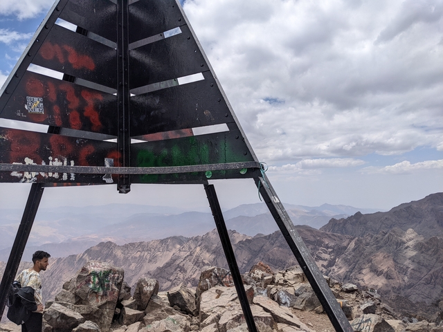 Summit marker on top of a mountain with a view of ranges.