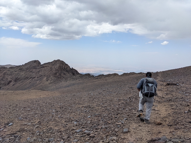       Hiker walking on a rocky mountain path.
  