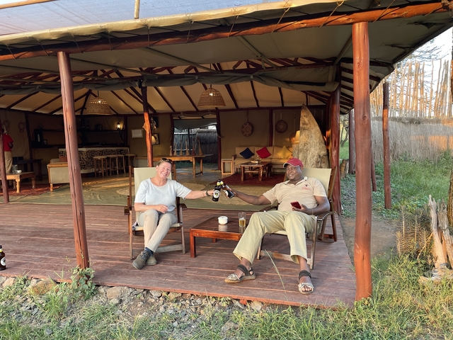 Two people enjoying drinks on a veranda overlooking nature.