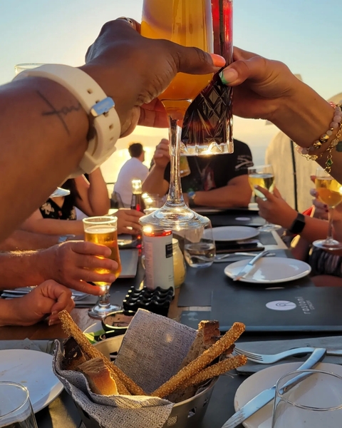 Close-up of people clinking their drinks at a table.