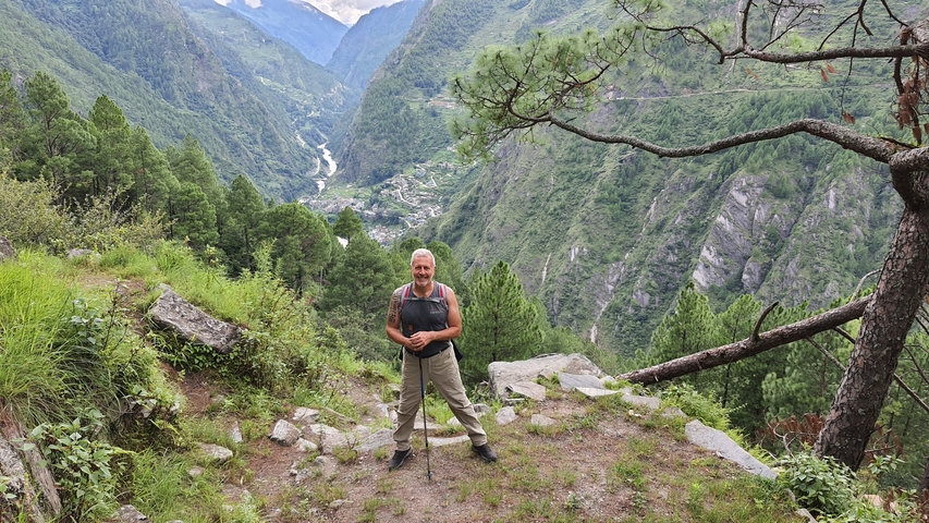 A person standing on a trail overlooking a lush valley.