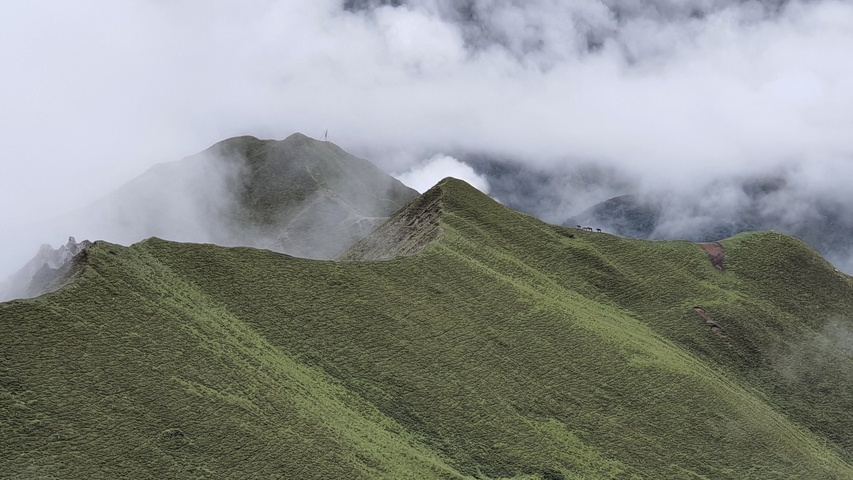 Cloud-covered mountain ridge with a lush green landscape.
