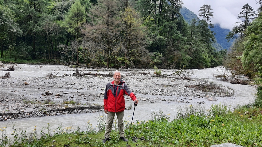       An individual with hiking gear near a river in a forested area.
  