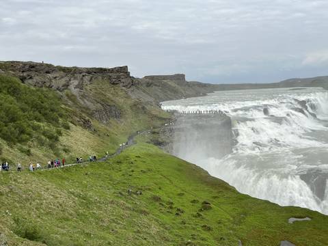 Large waterfall with people walking on the side trail.