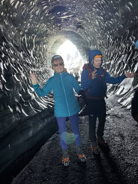 Two people inside an ice cave, wearing cold-weather gear.