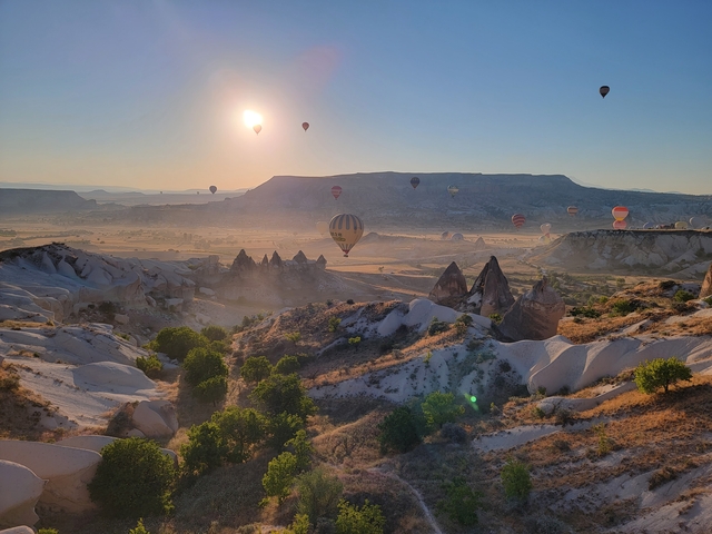 Hot air balloons float over Cappadocia's unique landscape at sunrise.