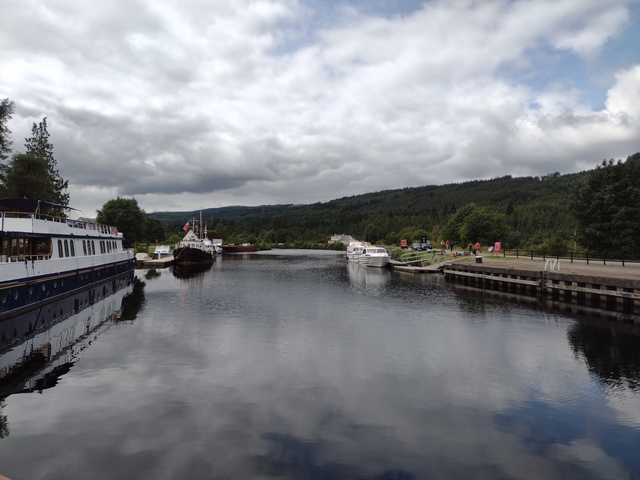 A peaceful canal scene with boats, surrounded by trees.