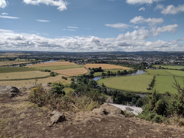 A landscape view of fields and a river in Scotland under a blue sky.