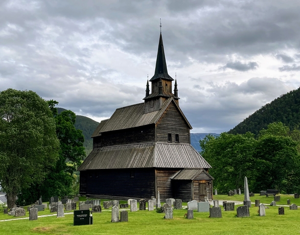       A wooden stave church set in a scenic landscape.
  
