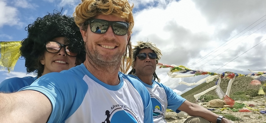 Group of people in colorful wigs on a mountain with flags.
