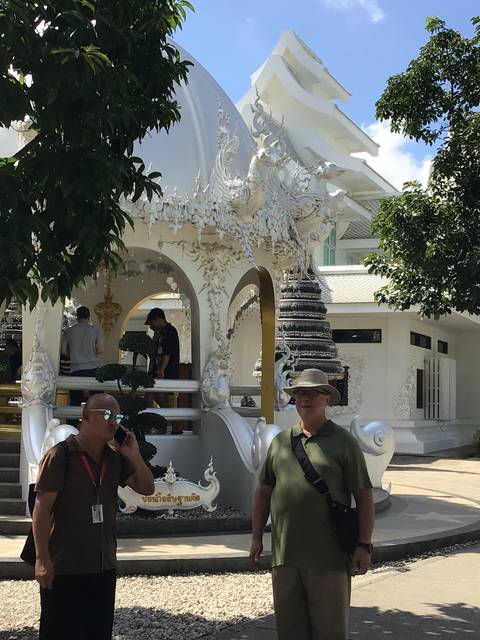       Tourists in front of a white ornate temple structure.
  