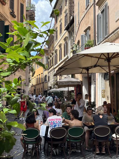       People dining outdoors at a street café.
  