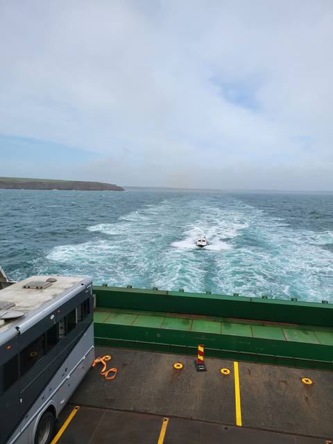       Boat cruising away on the ocean with a green deck.
  