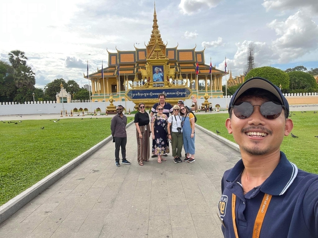 Tourists posing in front of a royal palace.