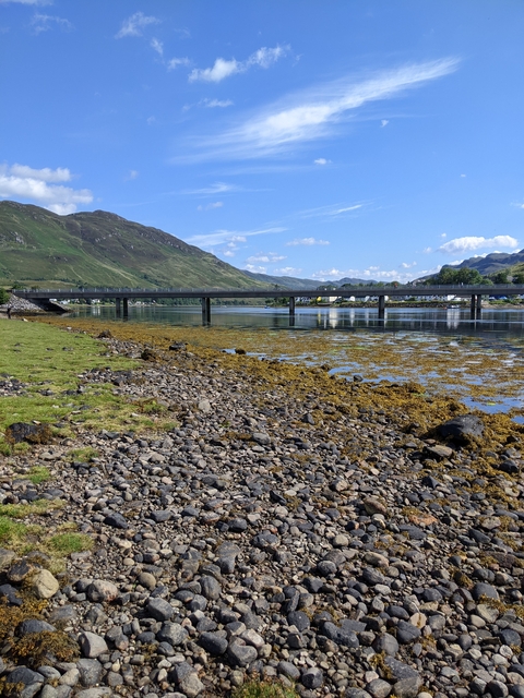 Bridge over a body of water with mountains in the background.
