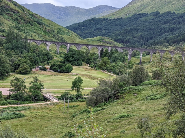       Historic viaduct in a lush green landscape.
  