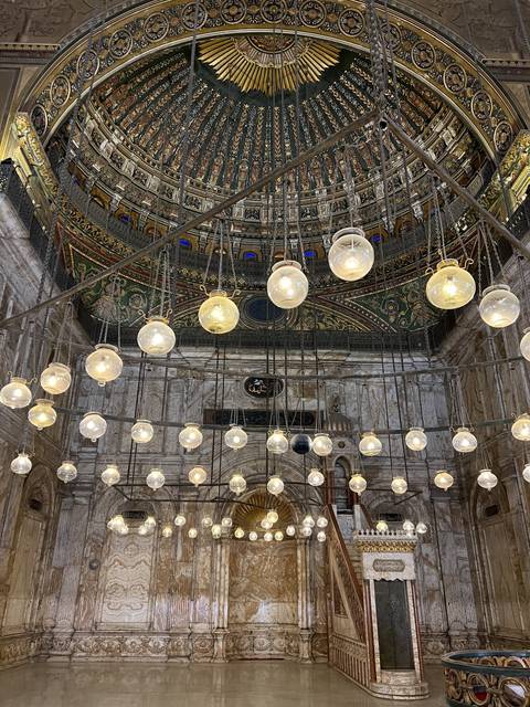       Colorful ceiling with intricate patterns and lamps in a mosque.
  