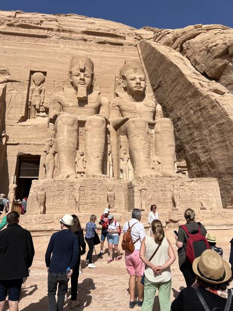       Tourists exploring a temple with large stone carvings.
  