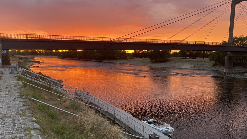 Sunset view of a bridge over a calm river.