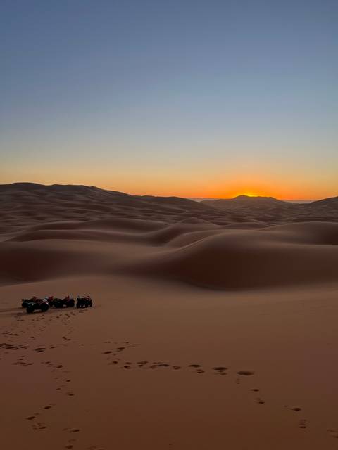 Sand dunes at sunset with footprints.