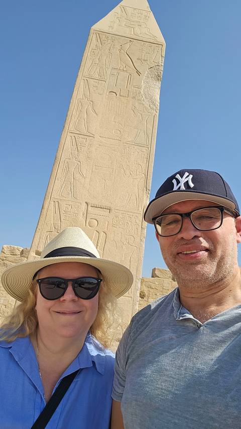       Two people taking a selfie with an obelisk in the background.
  