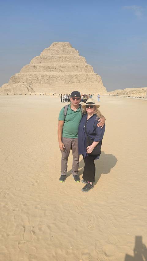 Two people posing with a pyramid in the background.