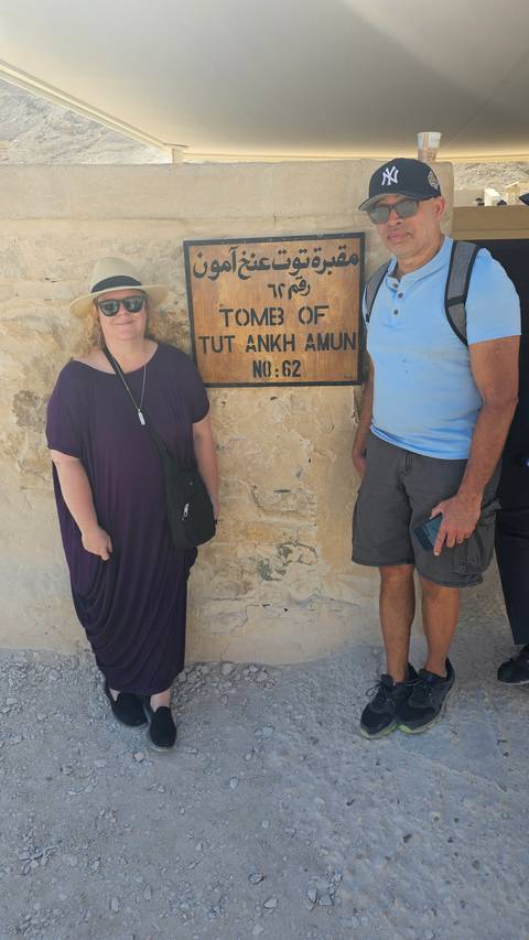       Two people posing by a sign for the Tomb of Tutankhamun.
  